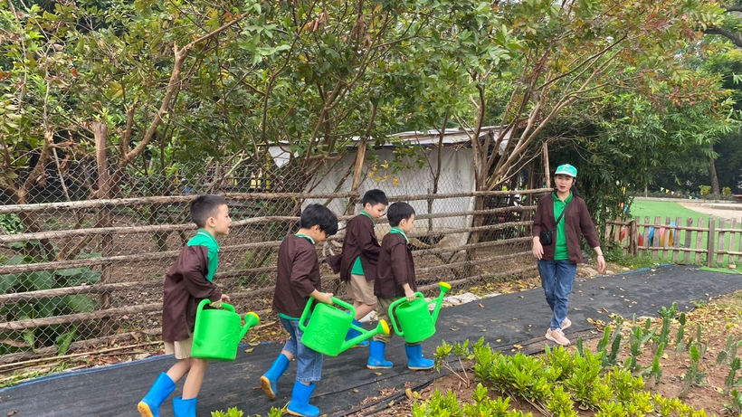 A group of children walking with watering cans

Description automatically generated
