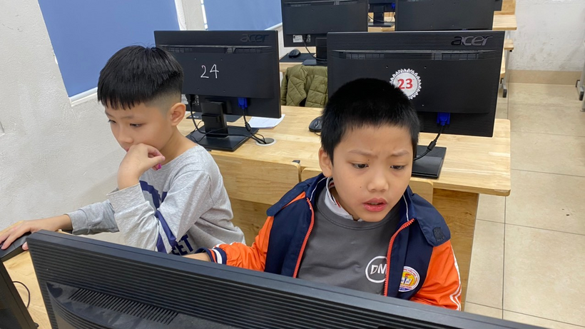 A group of boys sitting at a computer

Description automatically generated