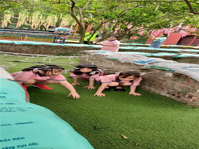 A group of girls in pink shirts on grass with spider webs

Description automatically generated
