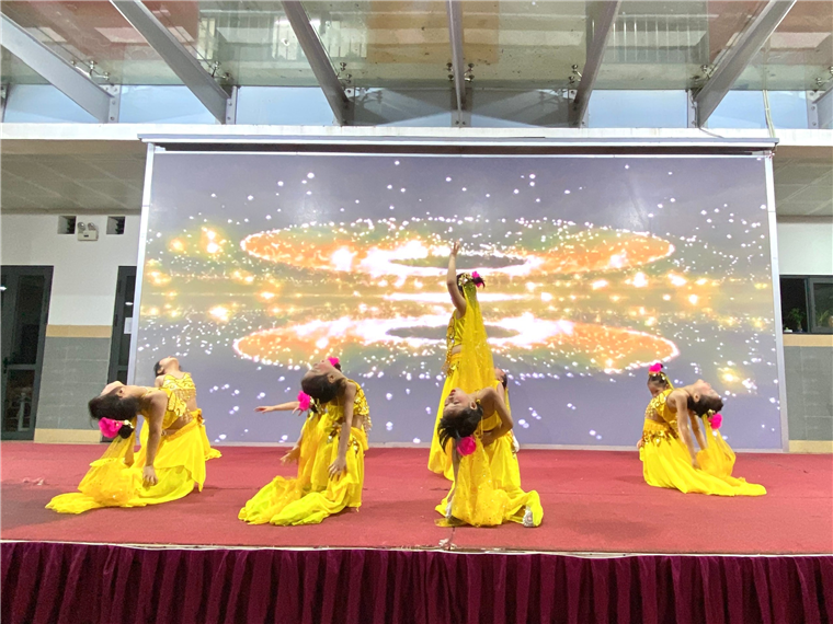 A group of women in yellow dresses on a stage

Description automatically generated