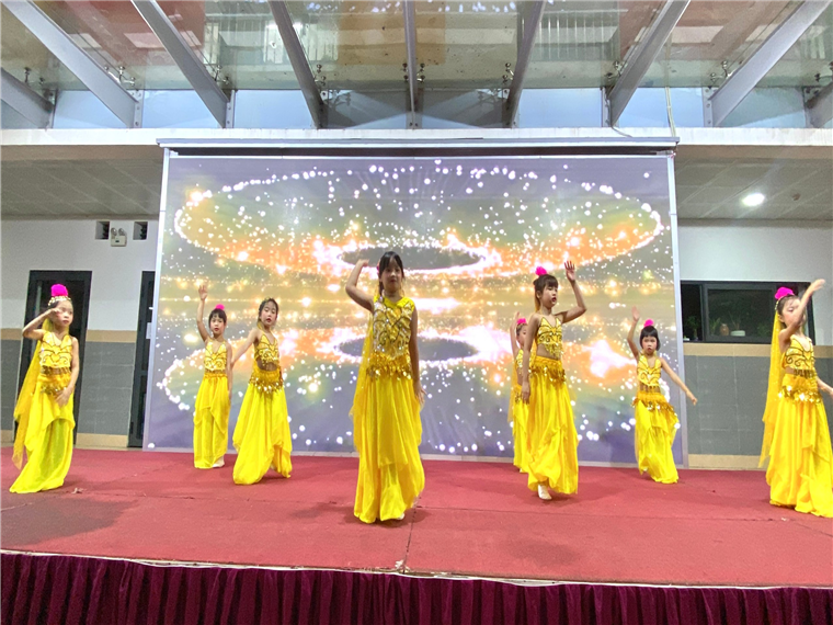 A group of girls in yellow dresses on a stage

Description automatically generated