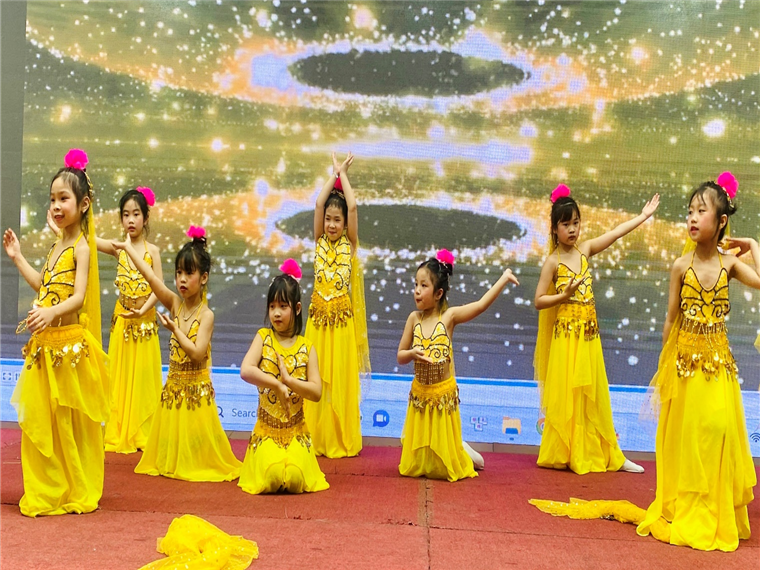 A group of young girls in yellow dresses on a stage

Description automatically generated